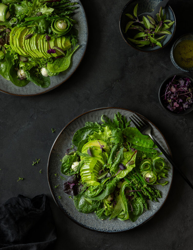 Zwei Teller mit Salatbowl mit Spargel und Avocado auf Tisch